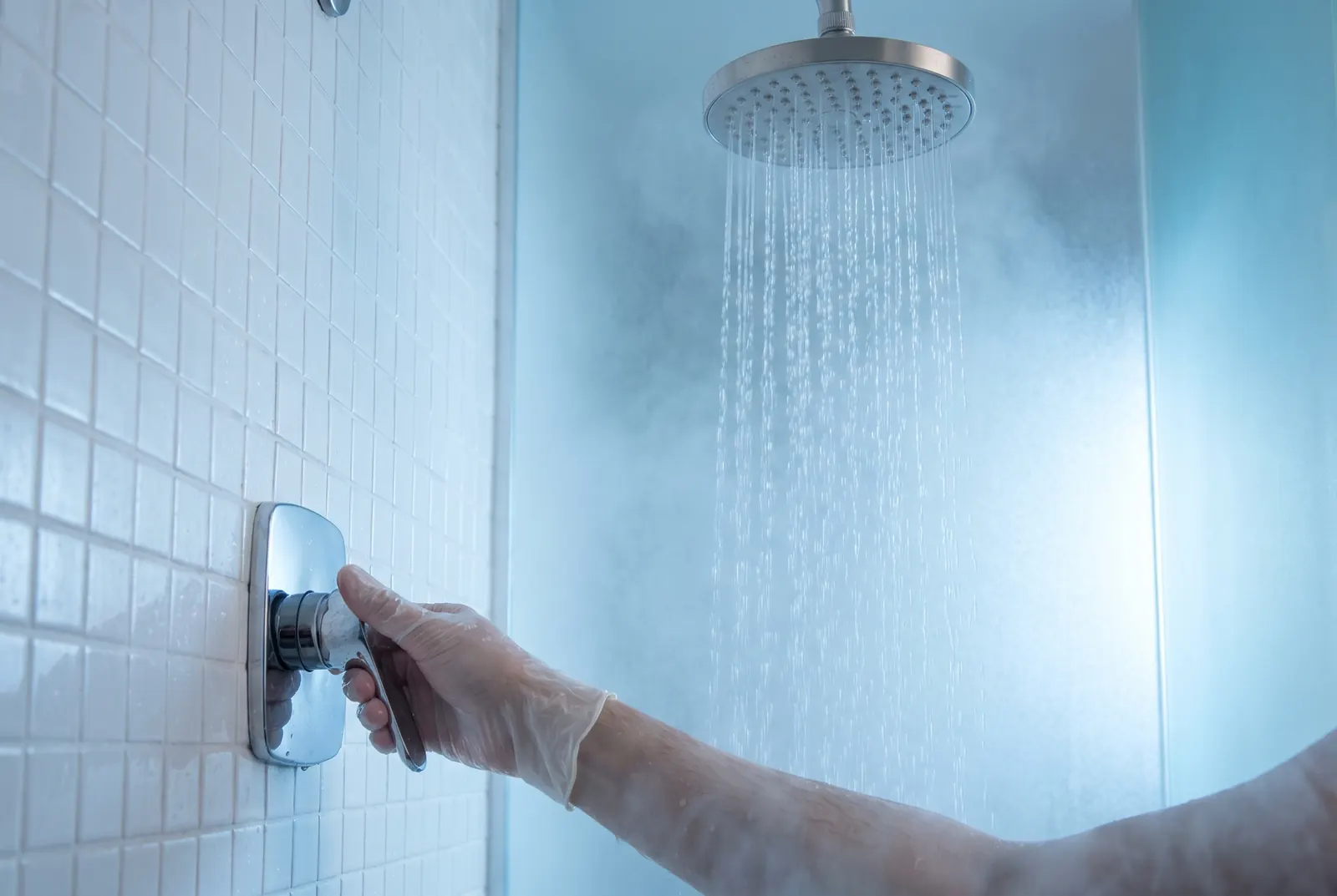 A hand turning a single-lever shower handle while the shower runs A hand turning a single-lever shower handle while the shower runs