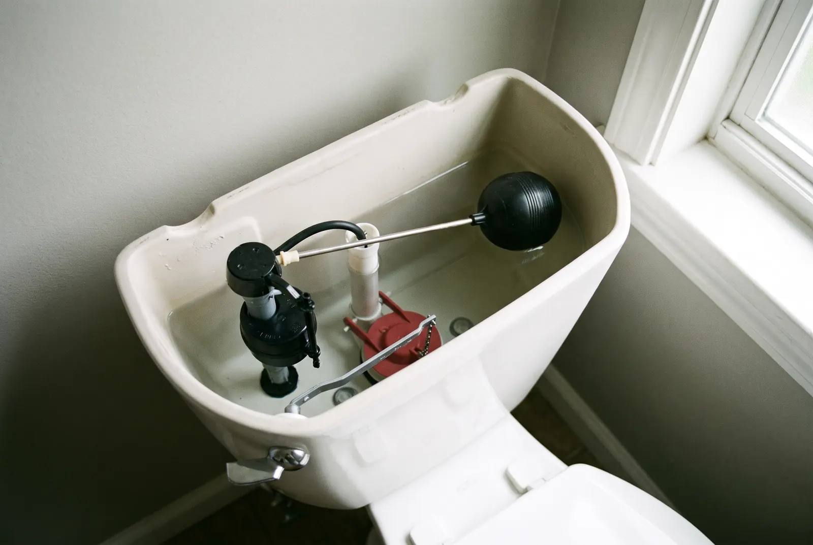Looking down into an open toilet tank at the fill valve, float and flapper Looking down into an open toilet tank at the fill valve, float and flapper